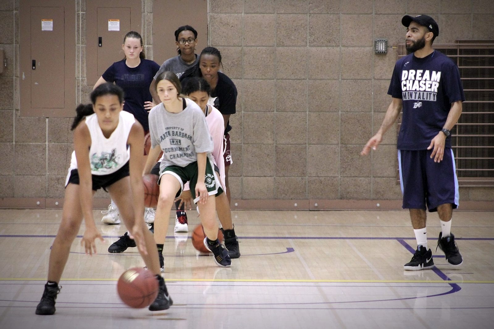 Dream Chaser athletes working through a ball handling drill while Coach Jelani watches